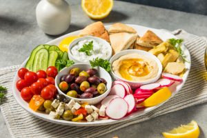 Authentic Middle Eastern mezze platter with hummus, tzatziki, olives, feta cheese, fresh vegetables, pita bread, and marinated artichokes.